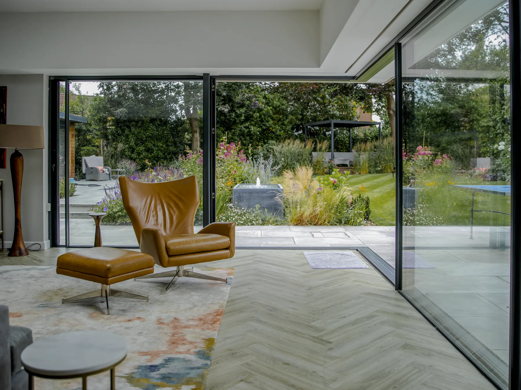 Living room in Esher opening onto the garden through slim sliding glass