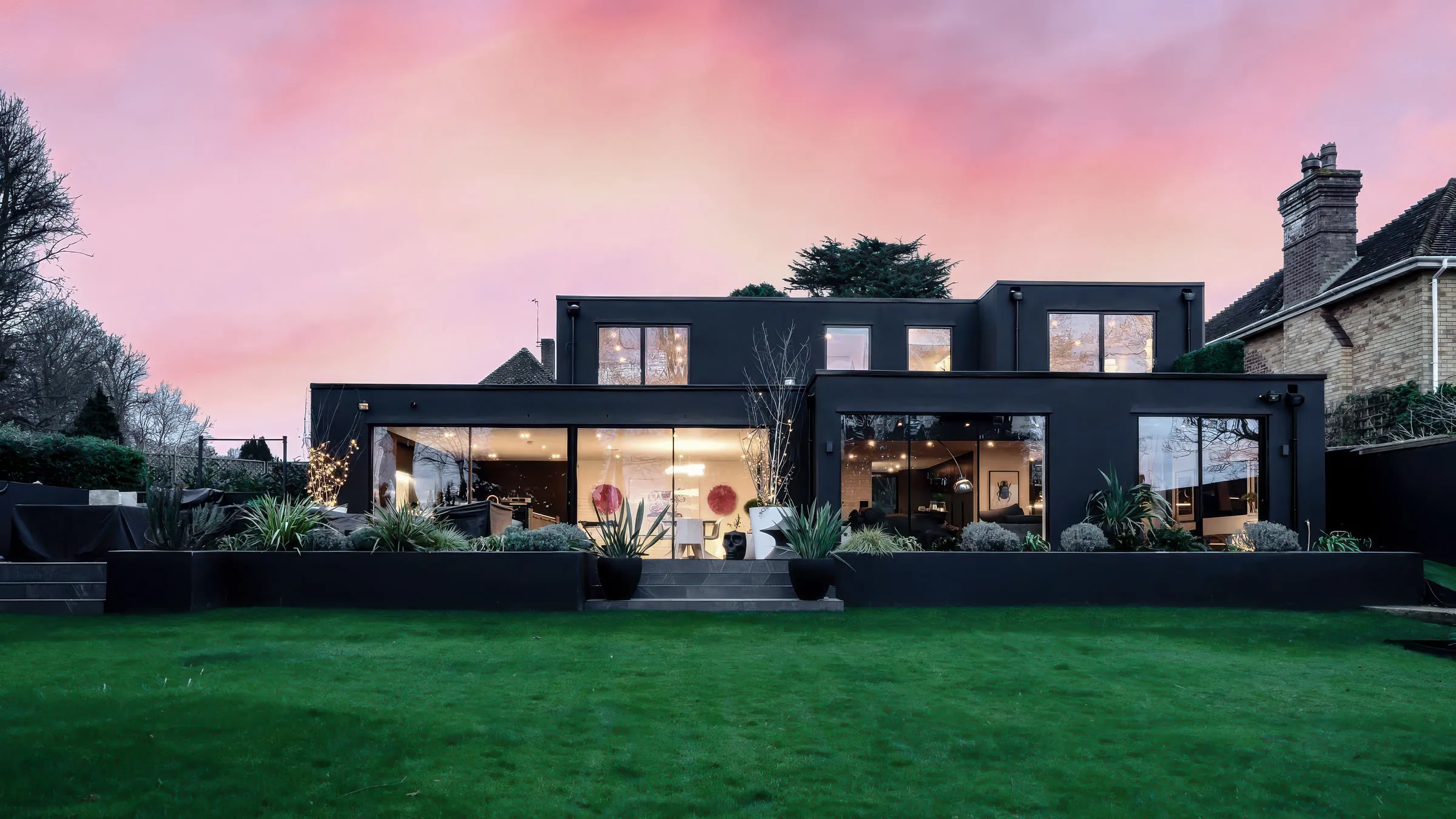A finished ADP rear extension at dusk, wide glazing across the back of the house